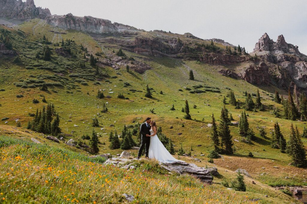 Bride and groom posing for Telluride elopement photos surrounded by greenery and wildflowers