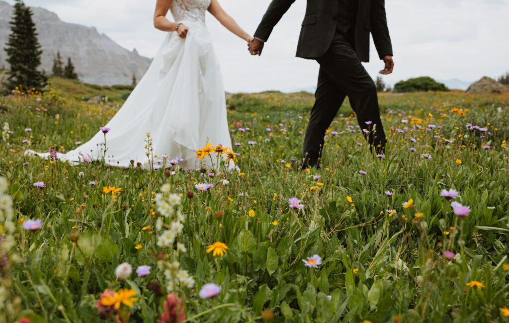 Bride and groom walking in wildflowers in Telluride