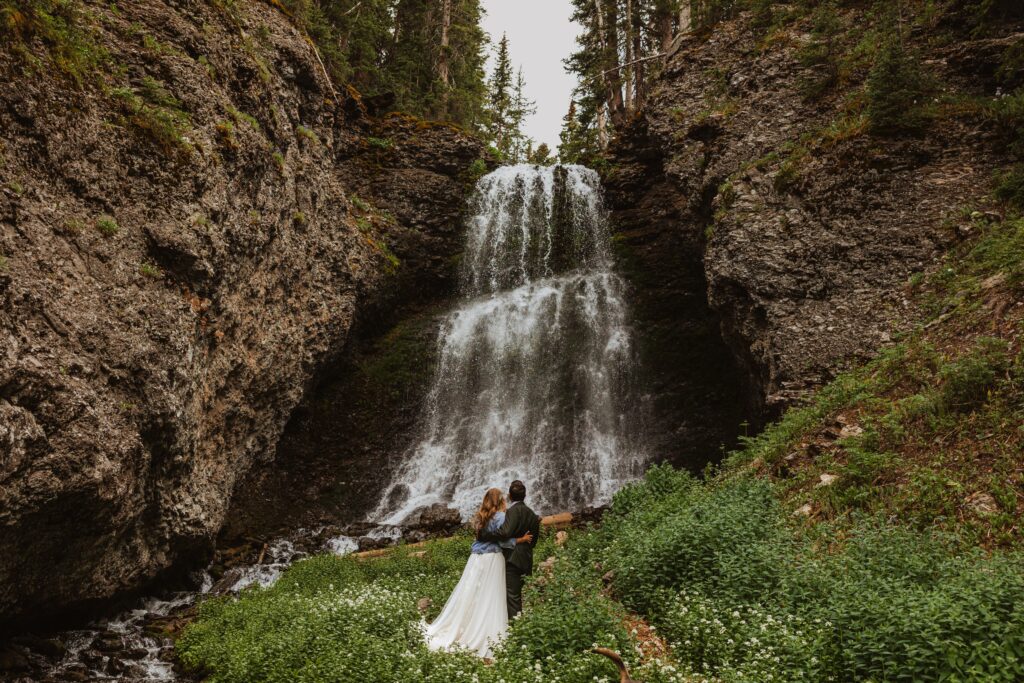 Bride and groom looking at Bridal Veil Falls for Telluride elopement photo