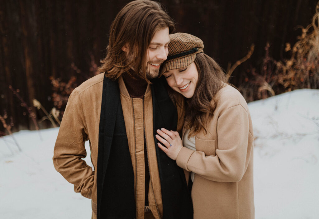 couple smiling and embracing for engagement photos in Denver
