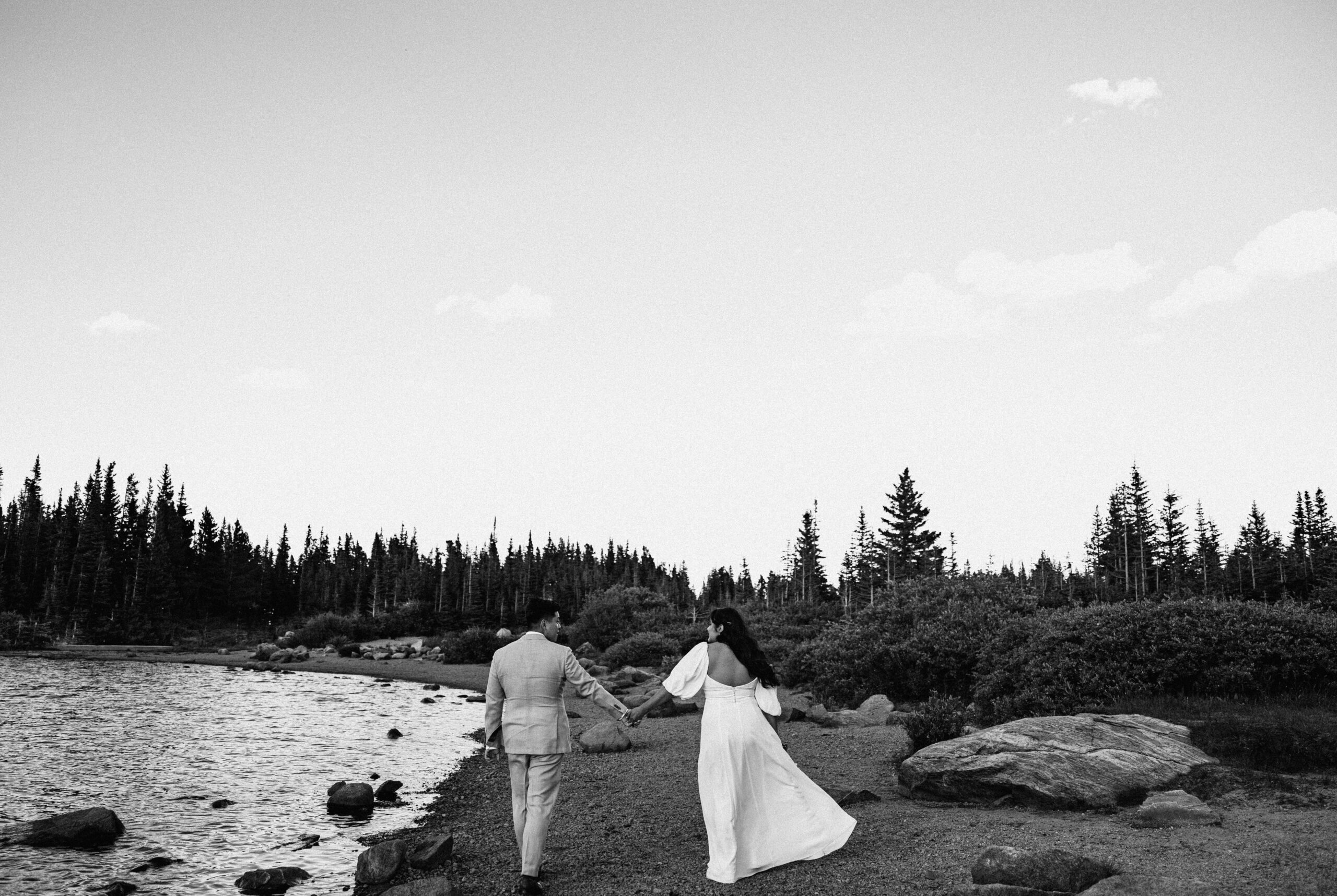 bride and groom beside Lake Brainard holding hands and walking a away from camera