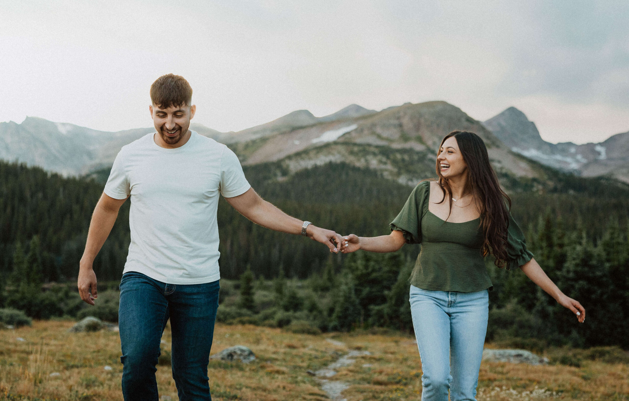 couple holding hands backed by mountains