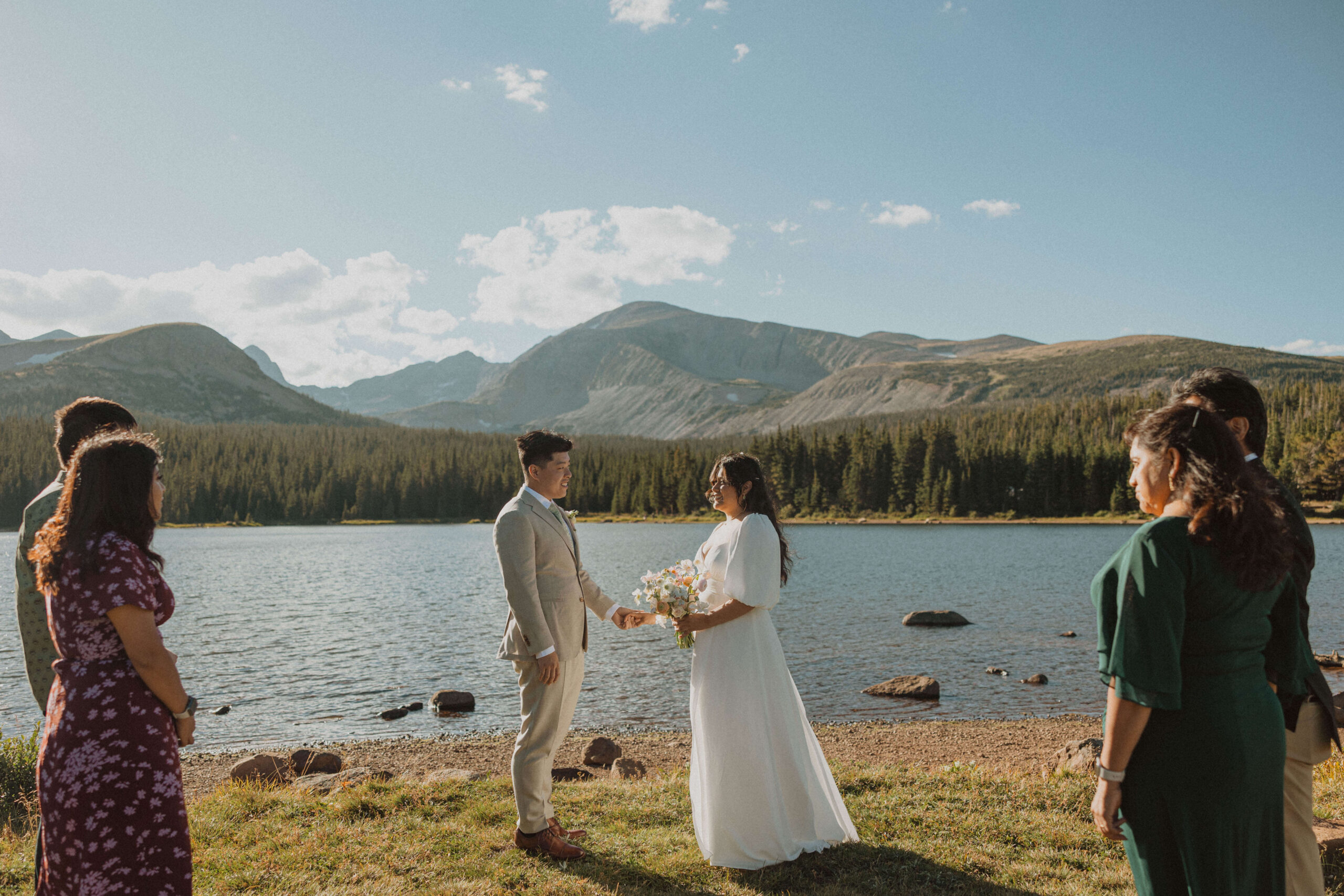 elopement couple holding hands with guests watching and mountain scenery in the back