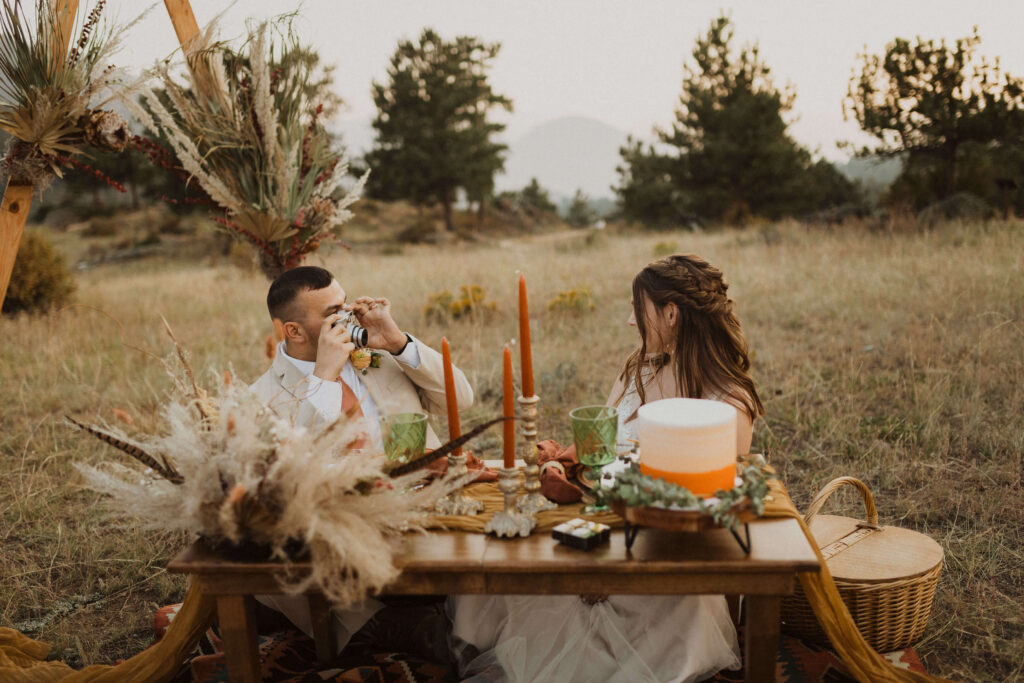 elopement couple sitting at table set up for a picnic at Rocky Mountain National Park