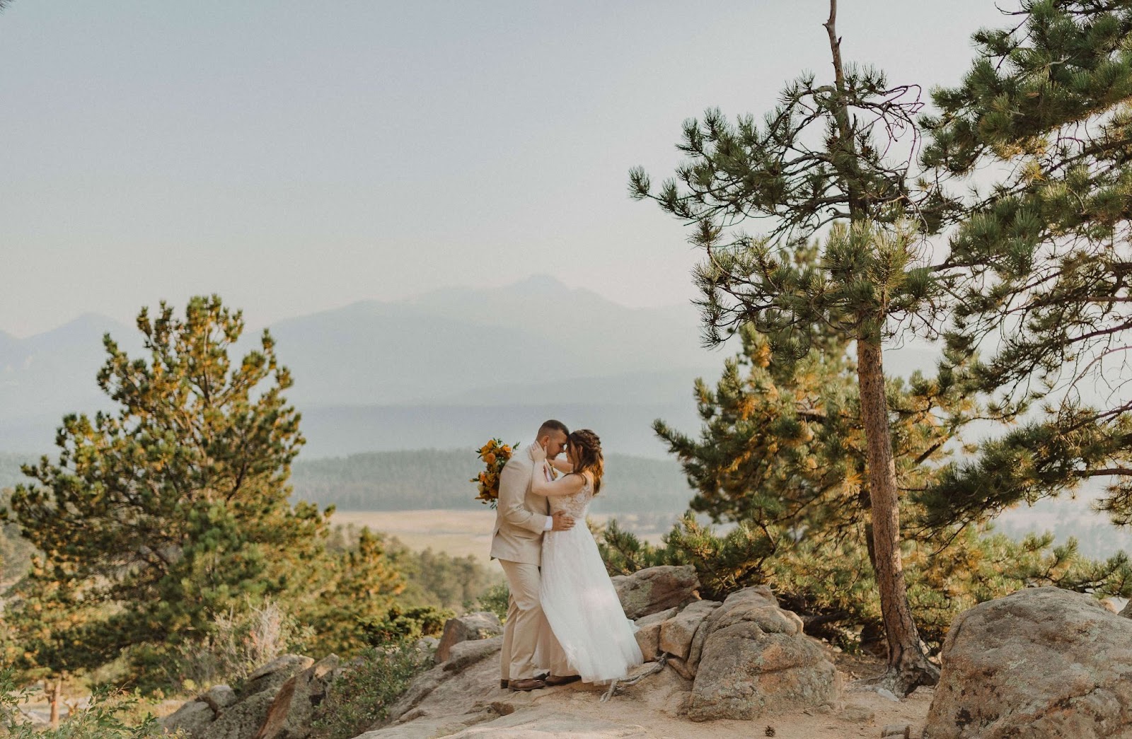 couple hugging and posing for Rocky Mountain National Park elopement photos with mountain backdrop