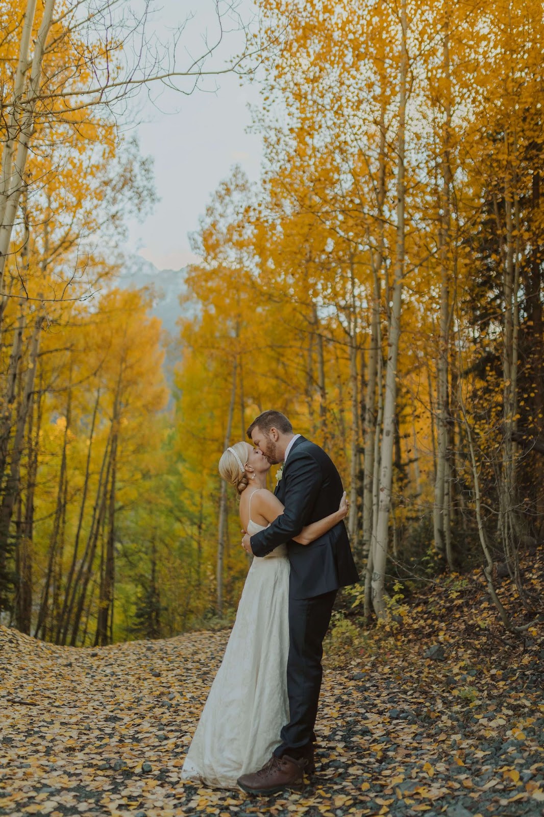 bride and groom hugging and kissing surrounded by fall trees and foliage for Ouray elopement