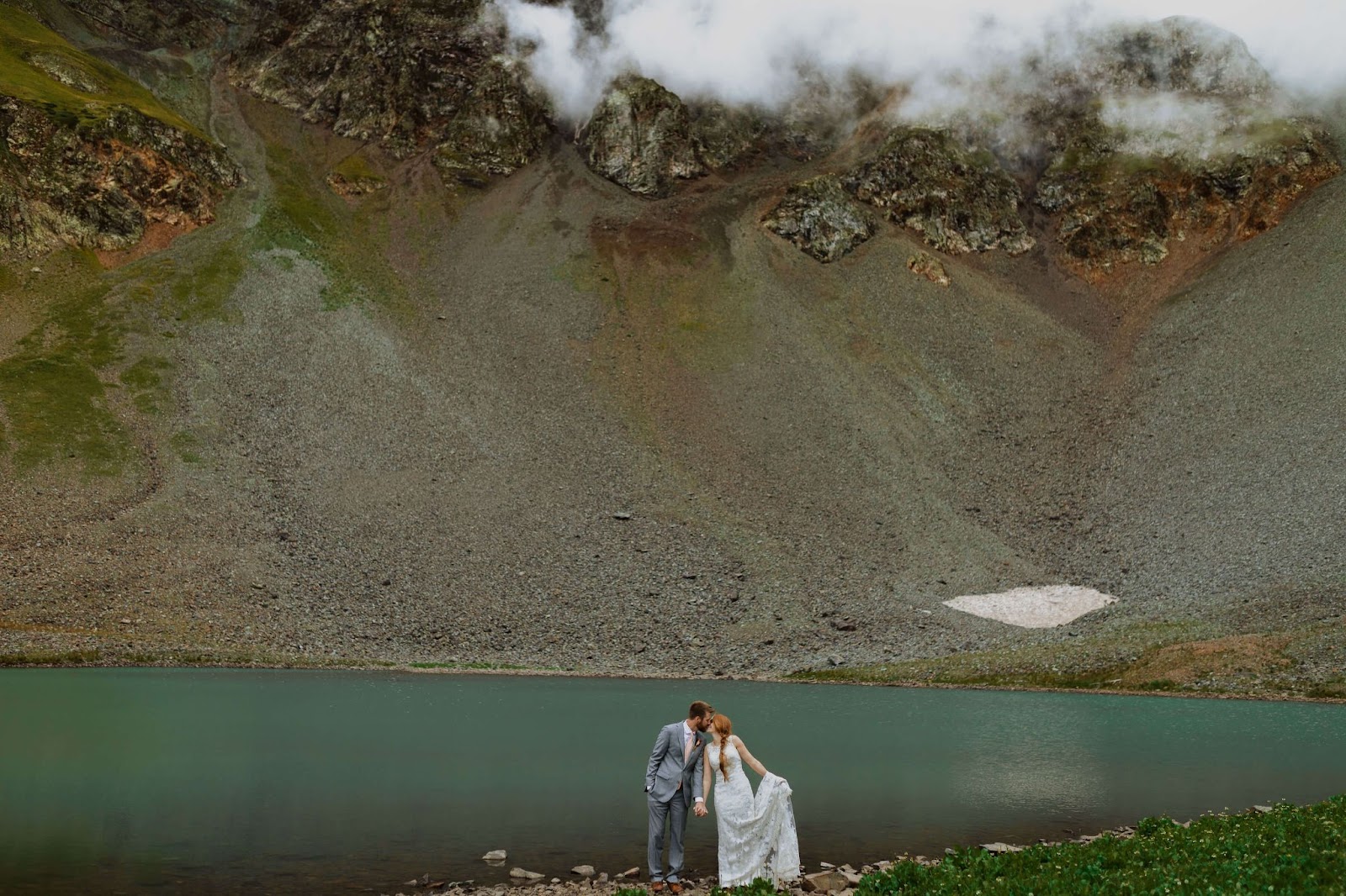 bride and groom kissing in Ouray infront of mountain and lake scenery