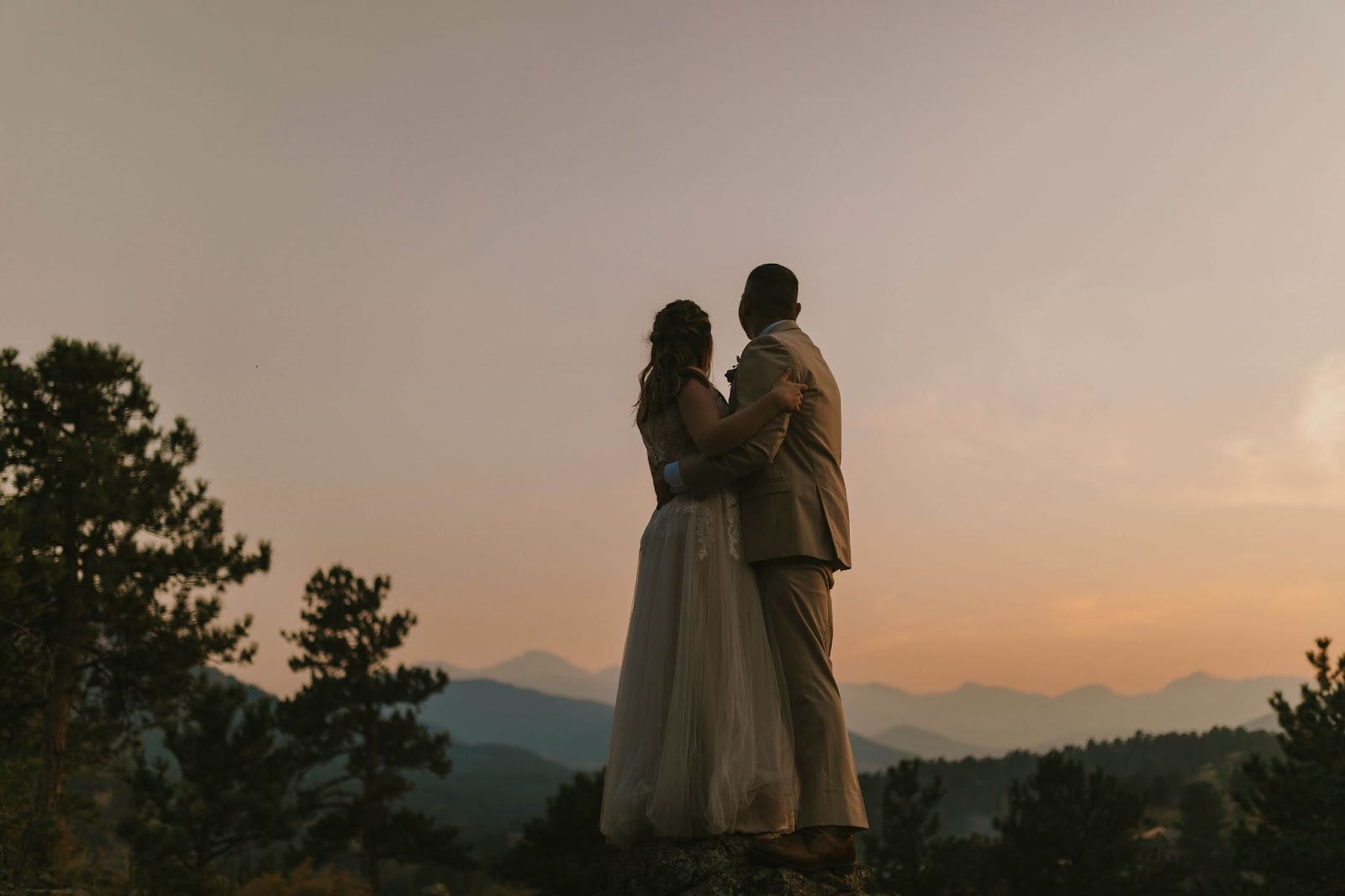 wedding couple embracing in front of snowy mountains