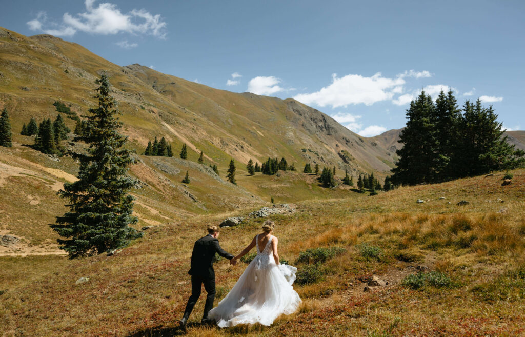 bride and groom walking together surrounded by mountains and trees for elopement in Ouray, Colorado