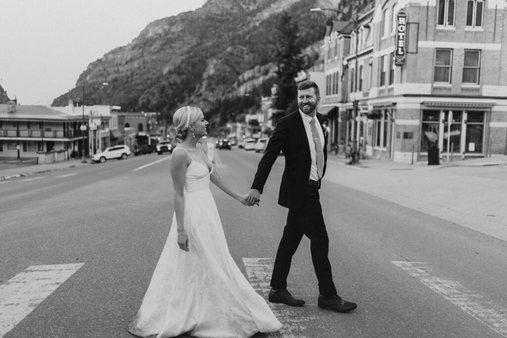 bride and groom walking and holding hands in downtown Ouray for elopement pictures
