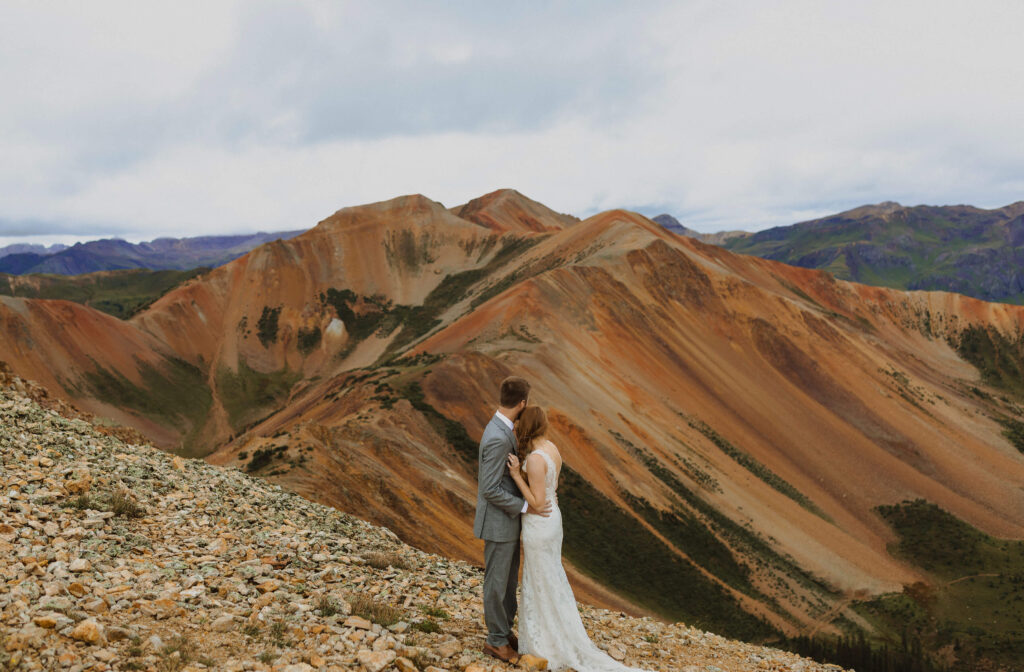 bride and groom hugging and looking at mountain scenery in Ouray, Colorado