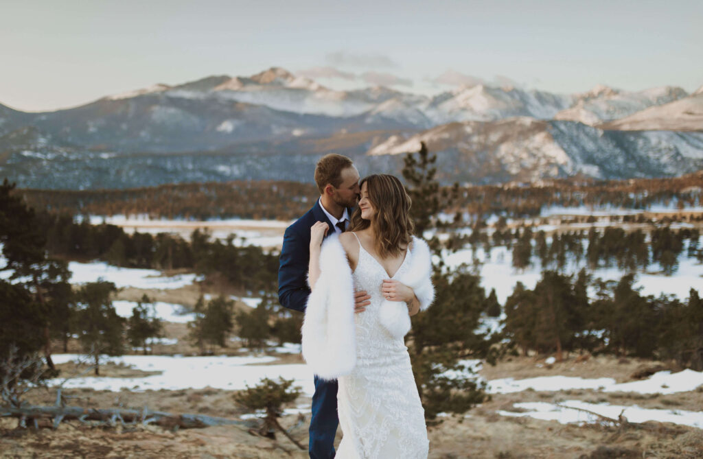 couple posing for Rocky Mountain National Park elopement photos with snowy mountains behind them