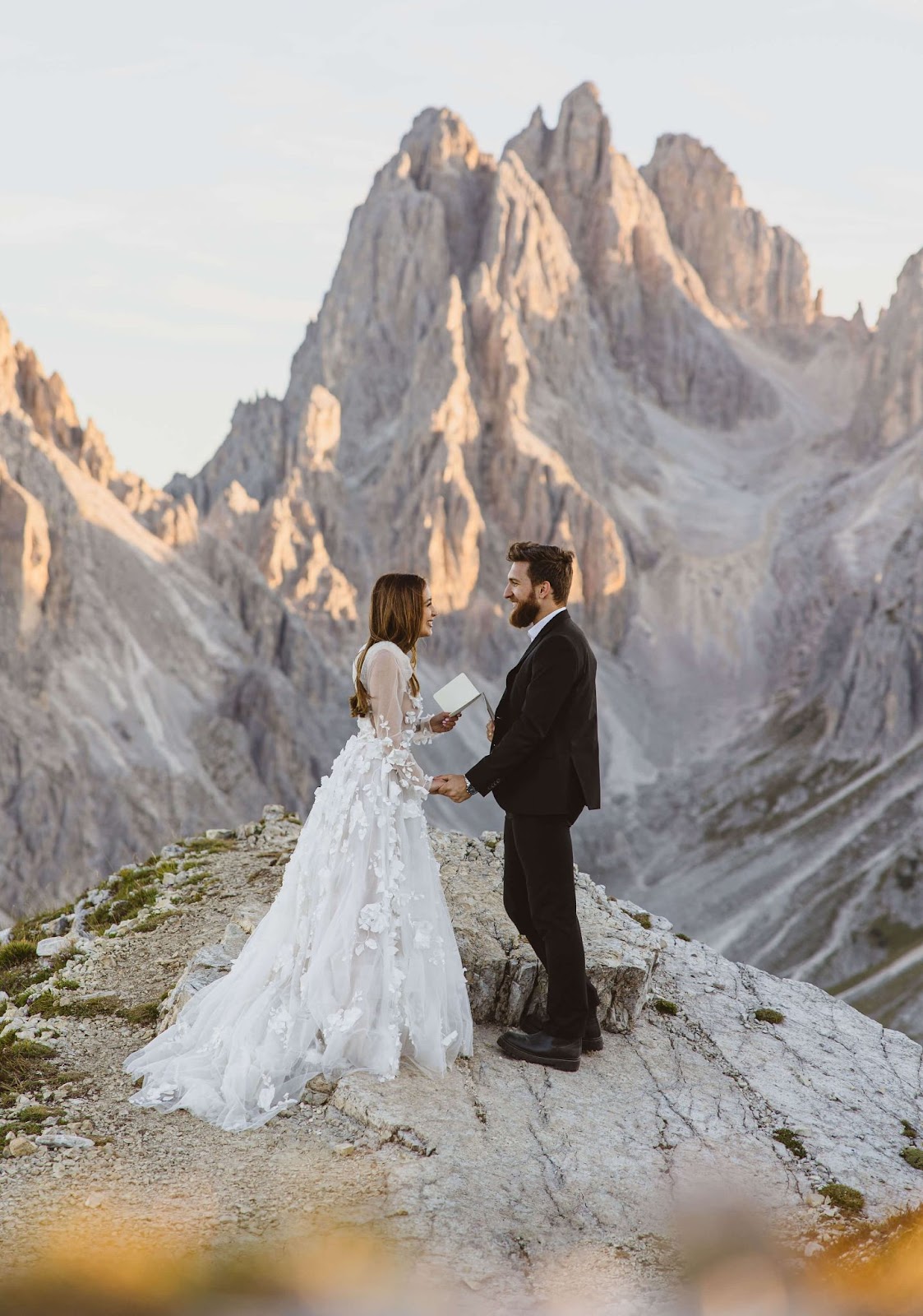 couple reading vows and smiling at eachother surrounded by mountain scenery for Dolomites elopement