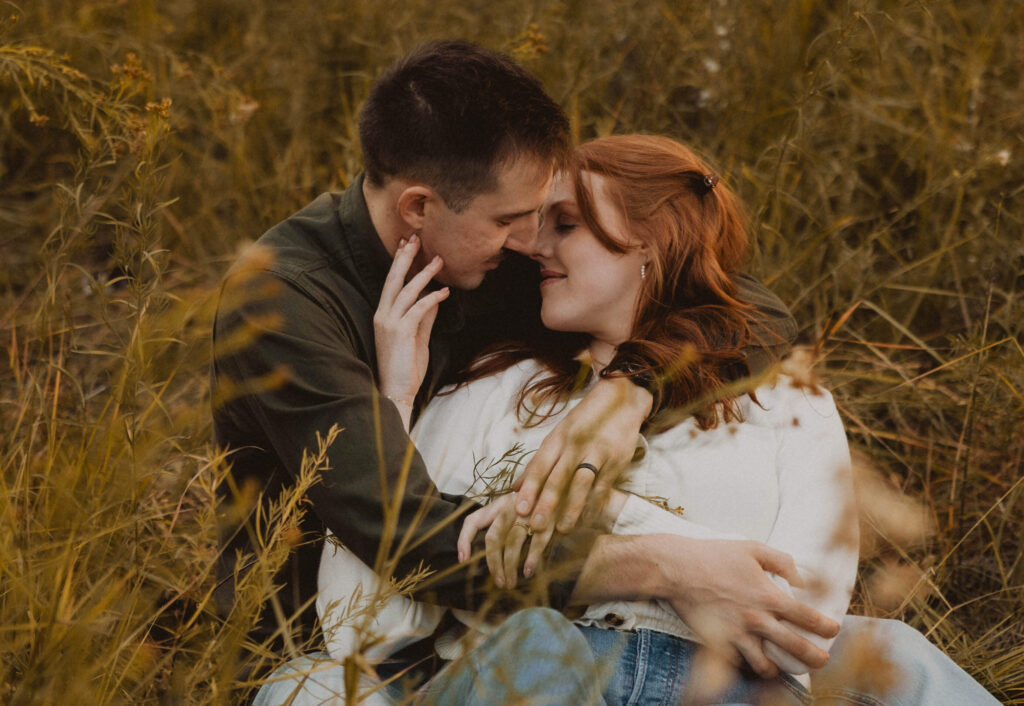 couple posing for picture lying in grass together