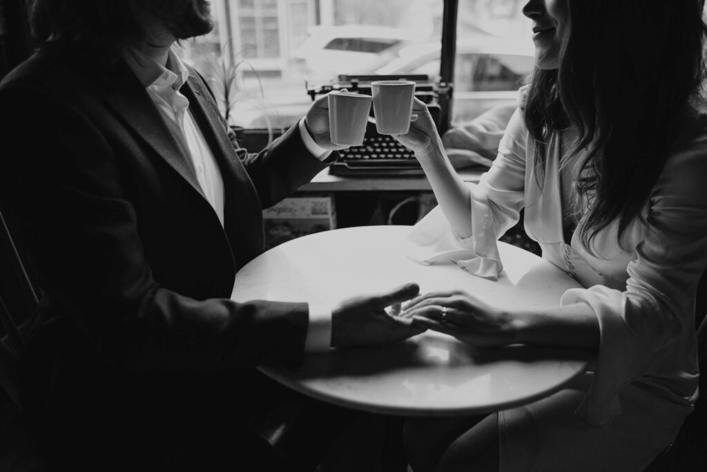 couple at coffee shop holding hands with mugs
