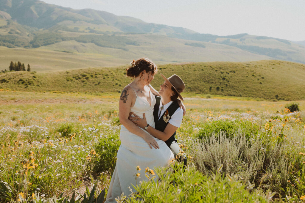 elopement couple posing and looking at each other in field with flowers
