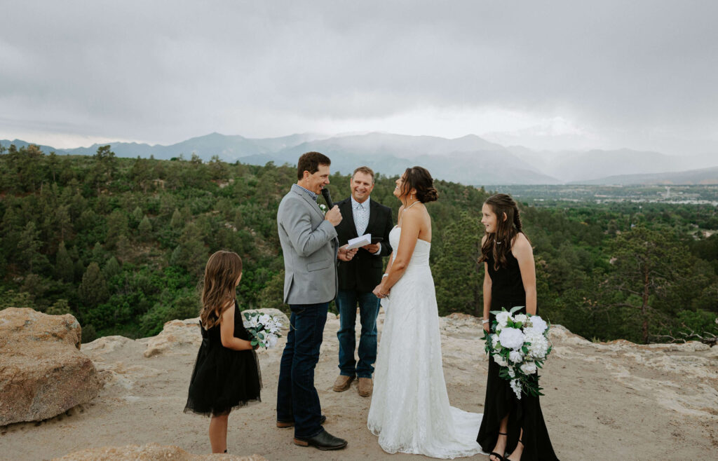 couple eloping at Palmer Park in front of mountain scenery with flower girls standing by them