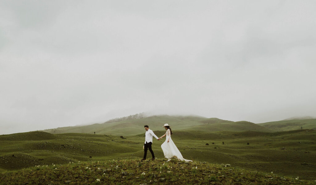 bride and groom holding hands surrounded by Montana scenery