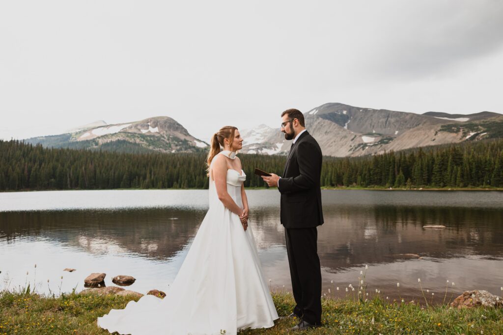 Groom reading vows to bride surrounded by mountains and lakes for Colorado micro wedding 