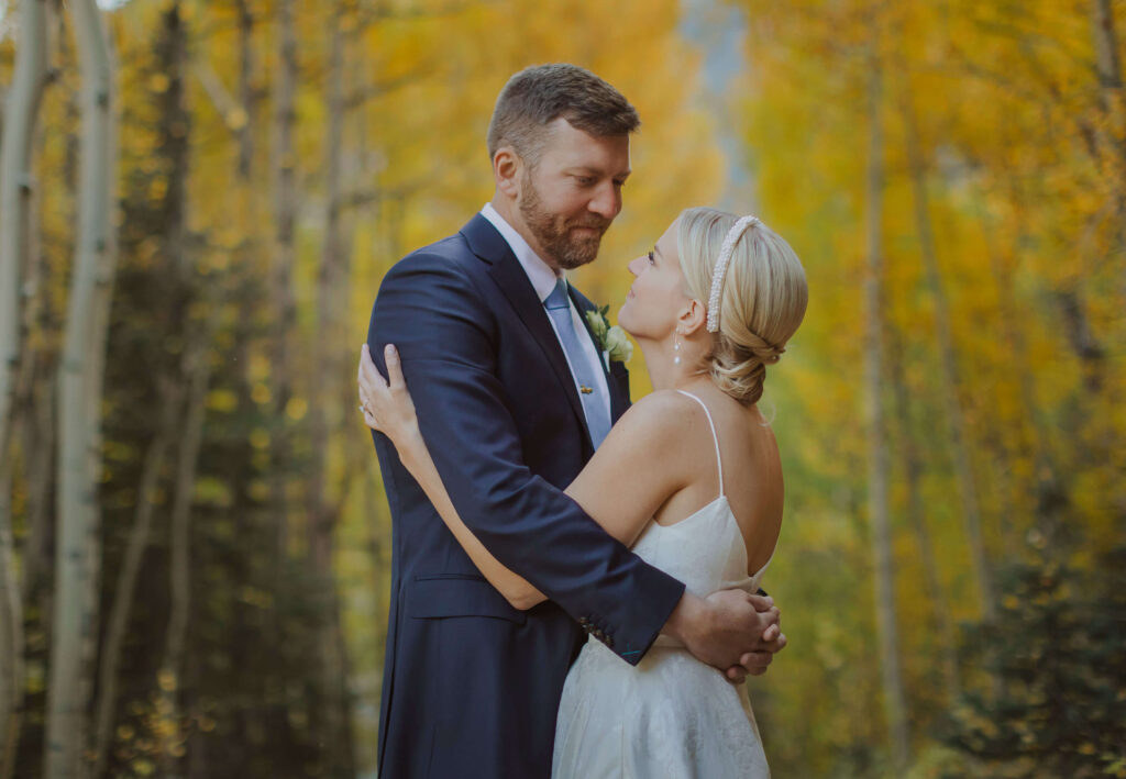 bride and groom hugging surrounded by trees