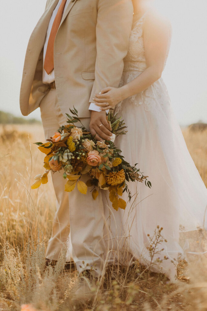bride and groom lower half of bodies holding wedding flowers