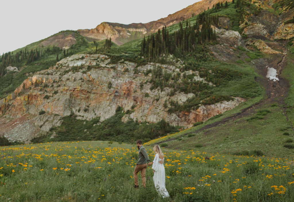 couple walking in field with flowers