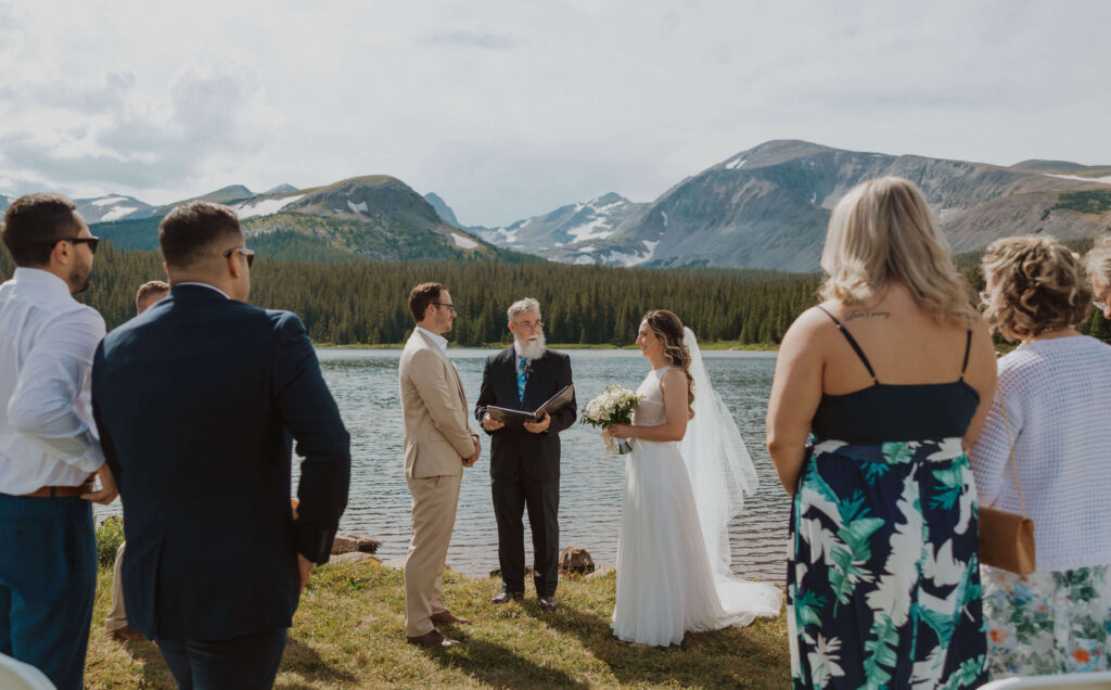 bride and groom getting married surrounded by guests at Brainard Lake in Colorado