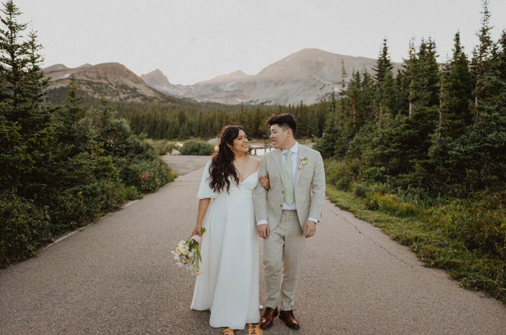 bride and groom posing on a road in front of a mountain