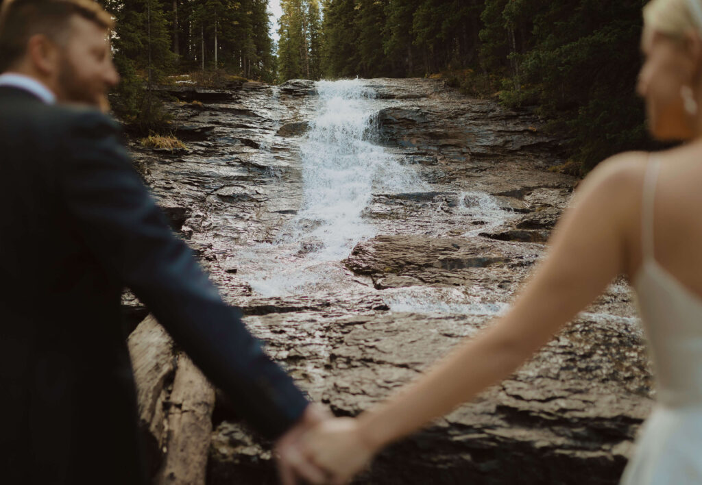 bride and groom facing waterfall