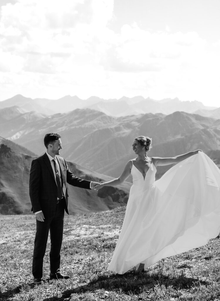 bride and groom smiling and looking at each other with mountain scenery behind them