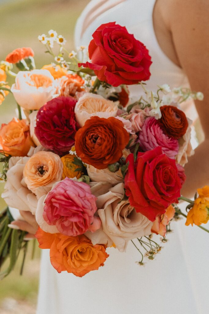 bride holding red and pink flowers