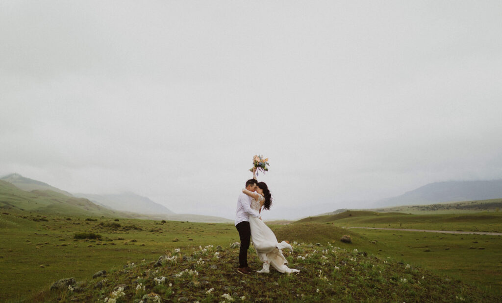 bride and groom in green field hugging