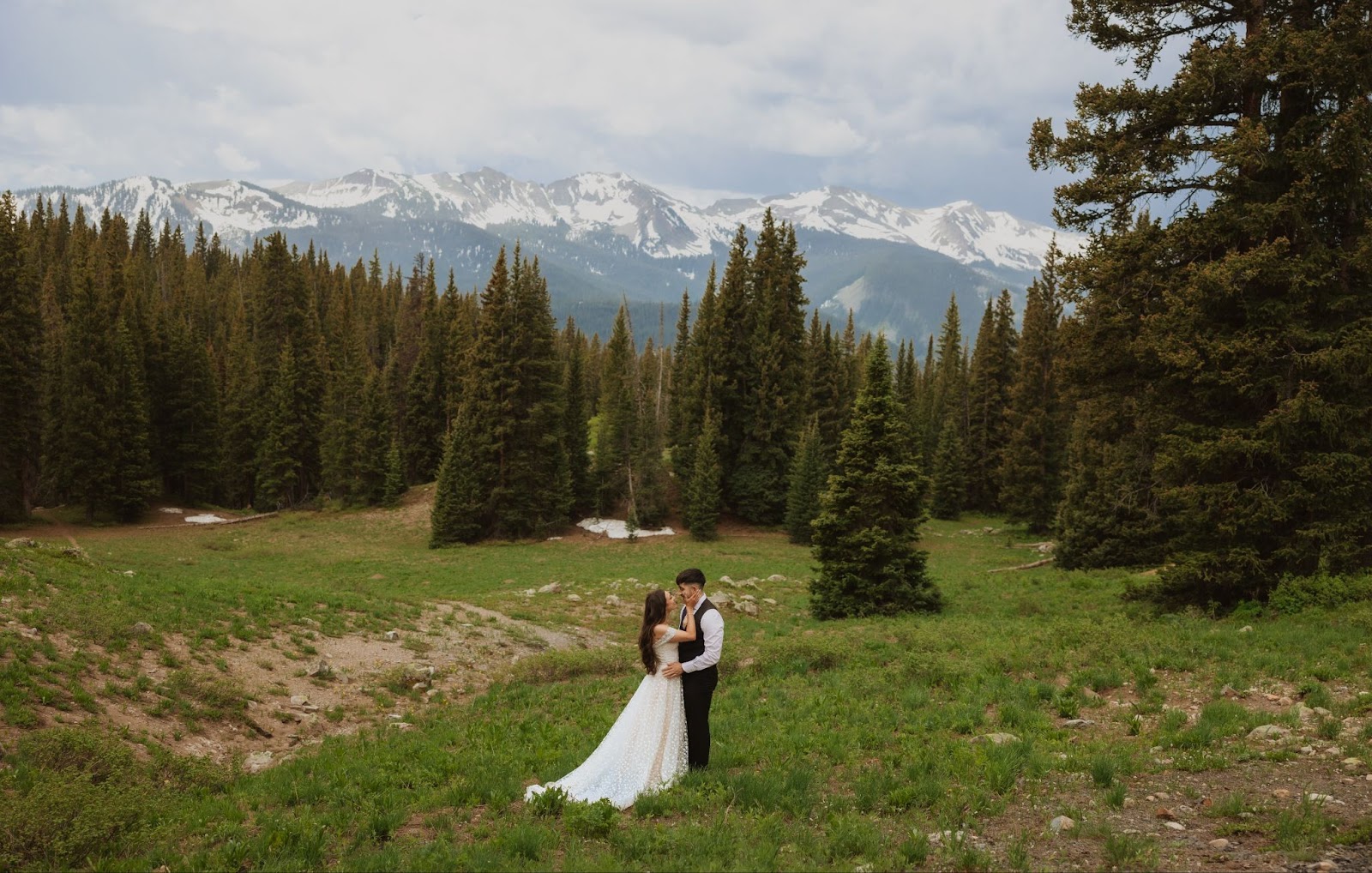 bride and groom backed by trees and mountains