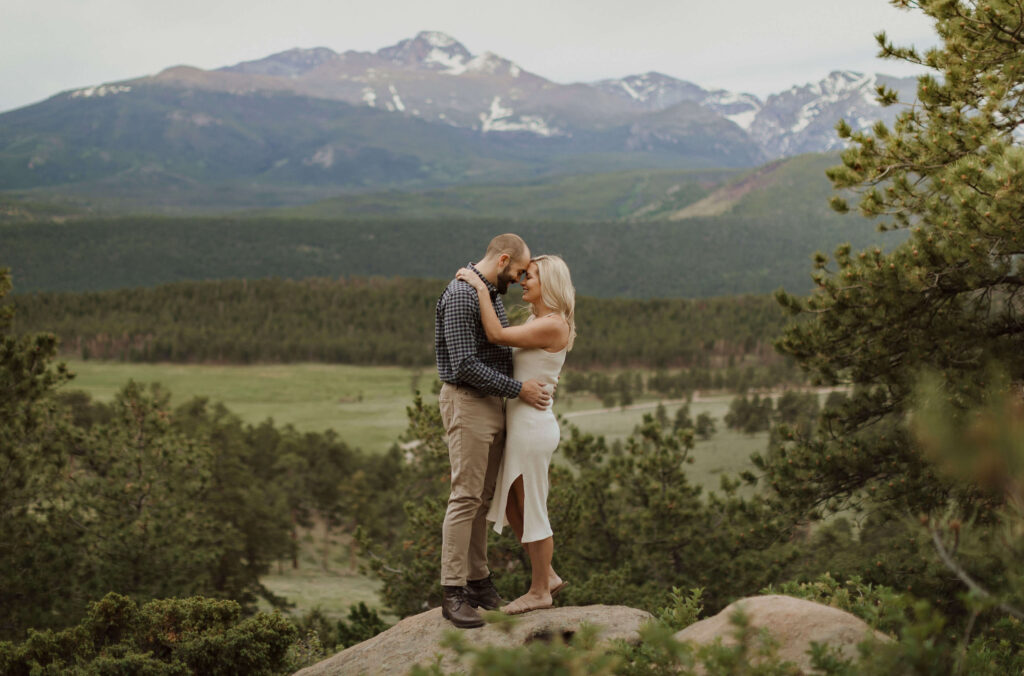 couple hugging surrounded by mountain scenery at Rocky Mountain National Park