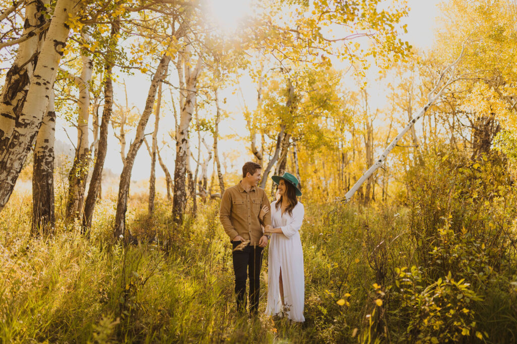 couple smiling at each other surrounded by trees at Rocky Mountain National Park