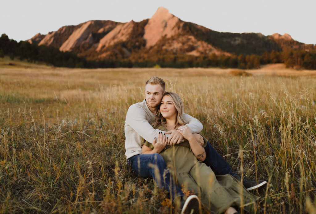 couple sitting in grass posing for engagement photos in Colorado