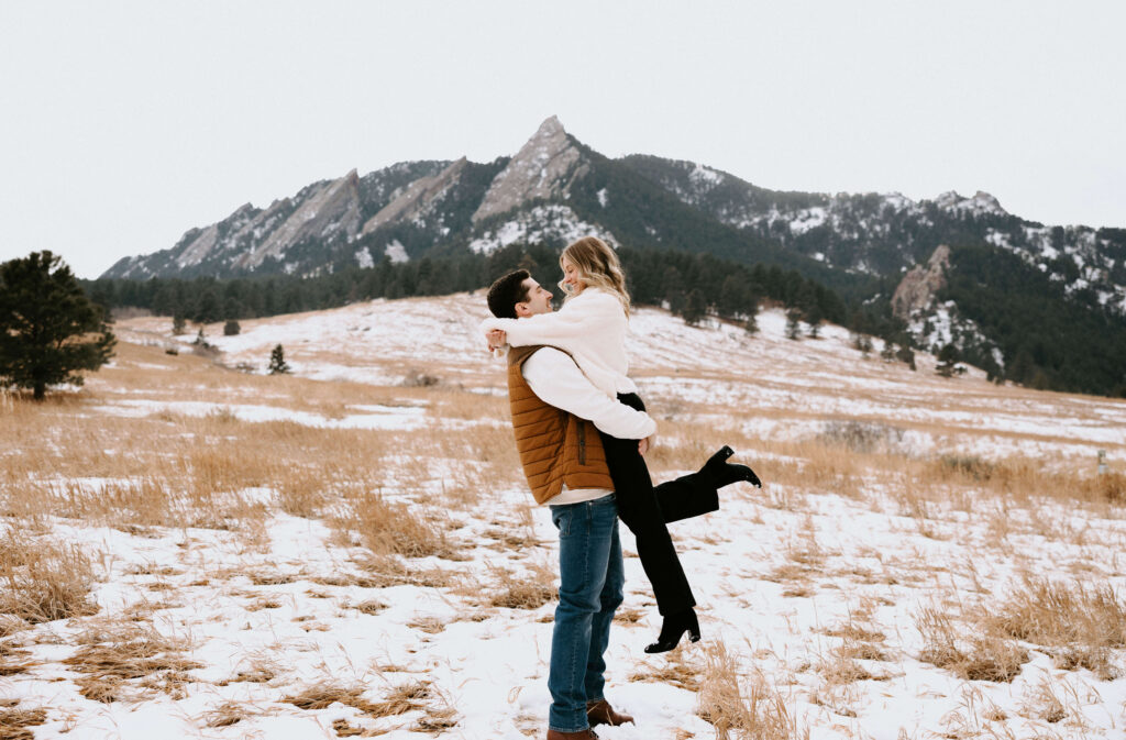 couple hugging surrounded by mountain scenery while posing for engagement photo session