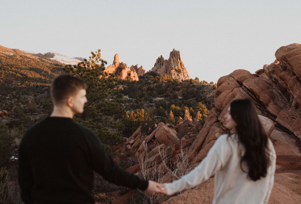 Couple holding hands and looking at each other while posing for engagement photos in Colorado at Garden of the Gods