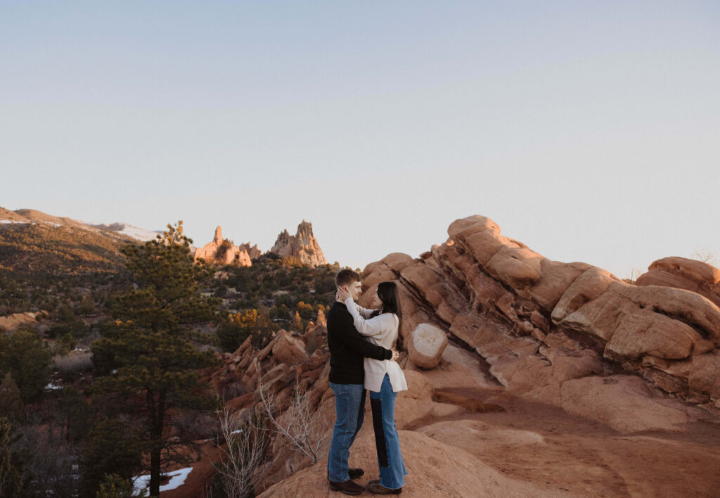 Couple hugging and looking at each other while posing for engagement photos in Colorado at Garden of the Gods