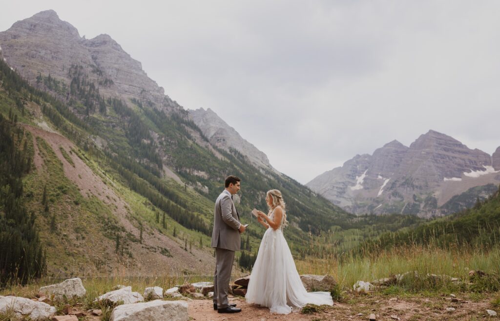 bride and groom reading vows backed by Maroon Bells mountain