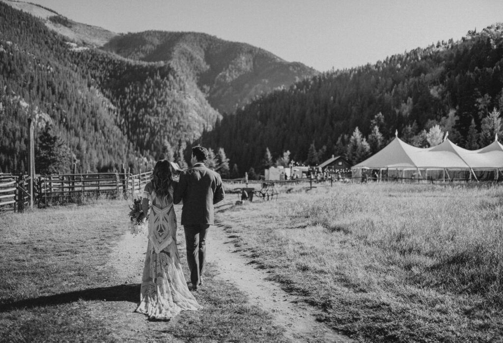 Bride and groom walking towards mountains at Cement Creek Ranch