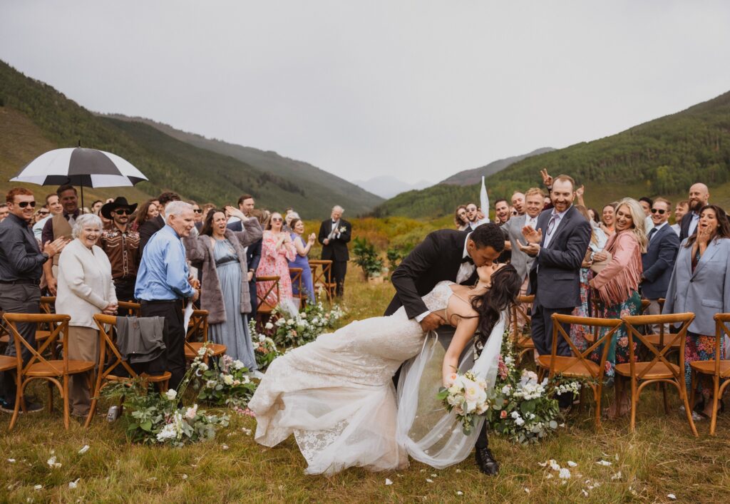 Couple kissing at wedding ceremony with guests watching at Cement Creek Ranch