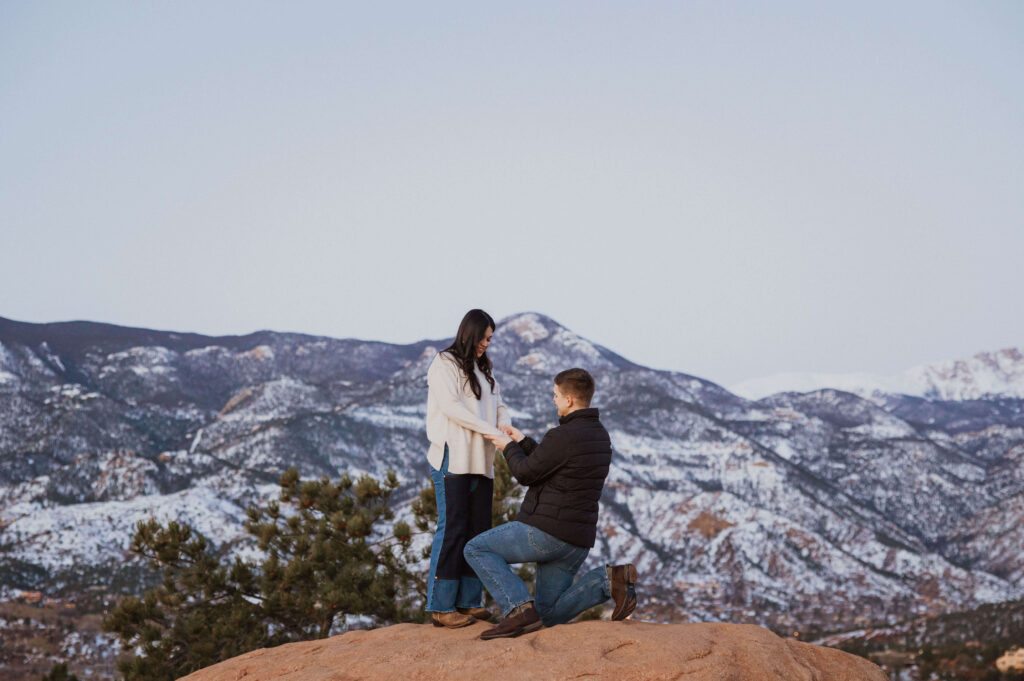 man proposing at Garden of the Gods backed my mountain scenery