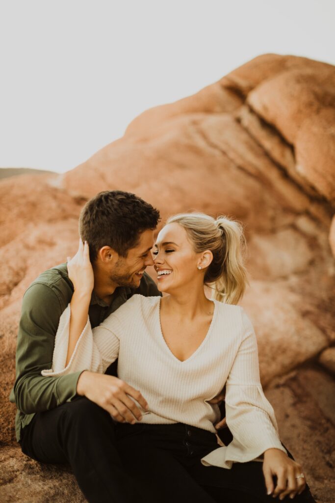 couple smiling at each other posing for Garden of the Gods engagement photos