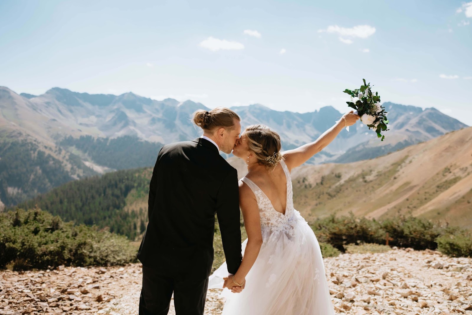 Bride and groom kissing and facing towards San Juan Mountains