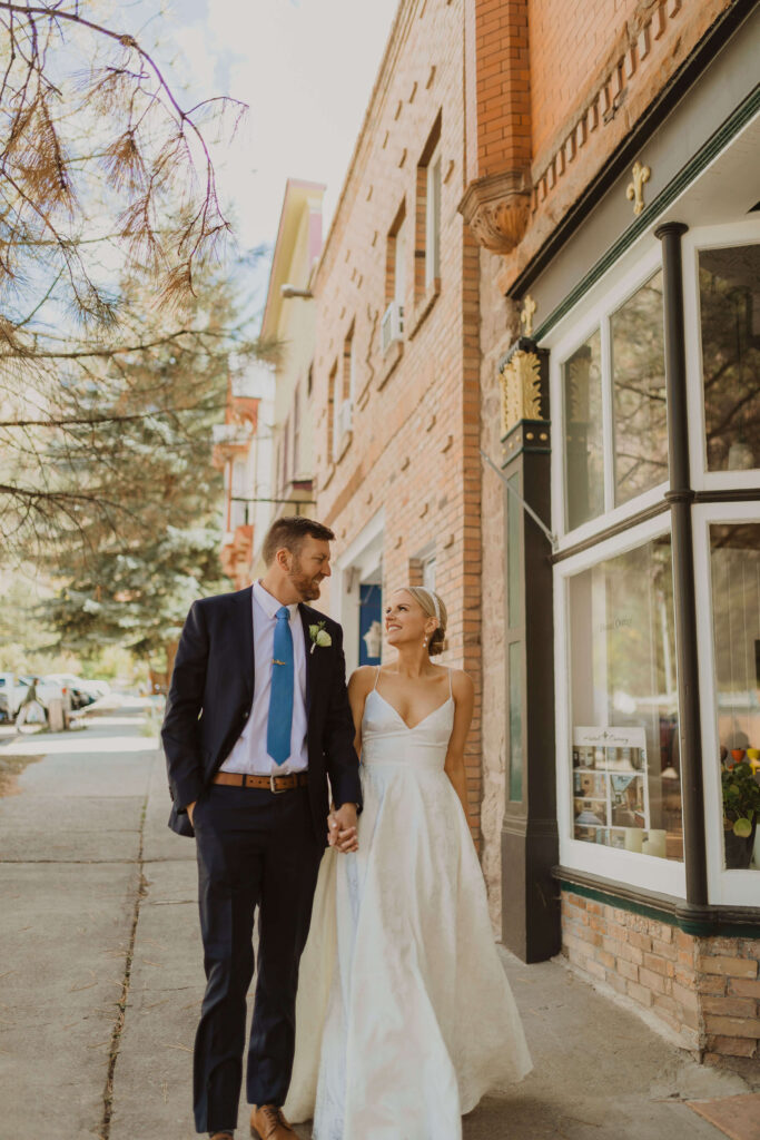 Bride and groom walking on sidewalk in front of The Beaumont Hotel in Ouray, Colorado