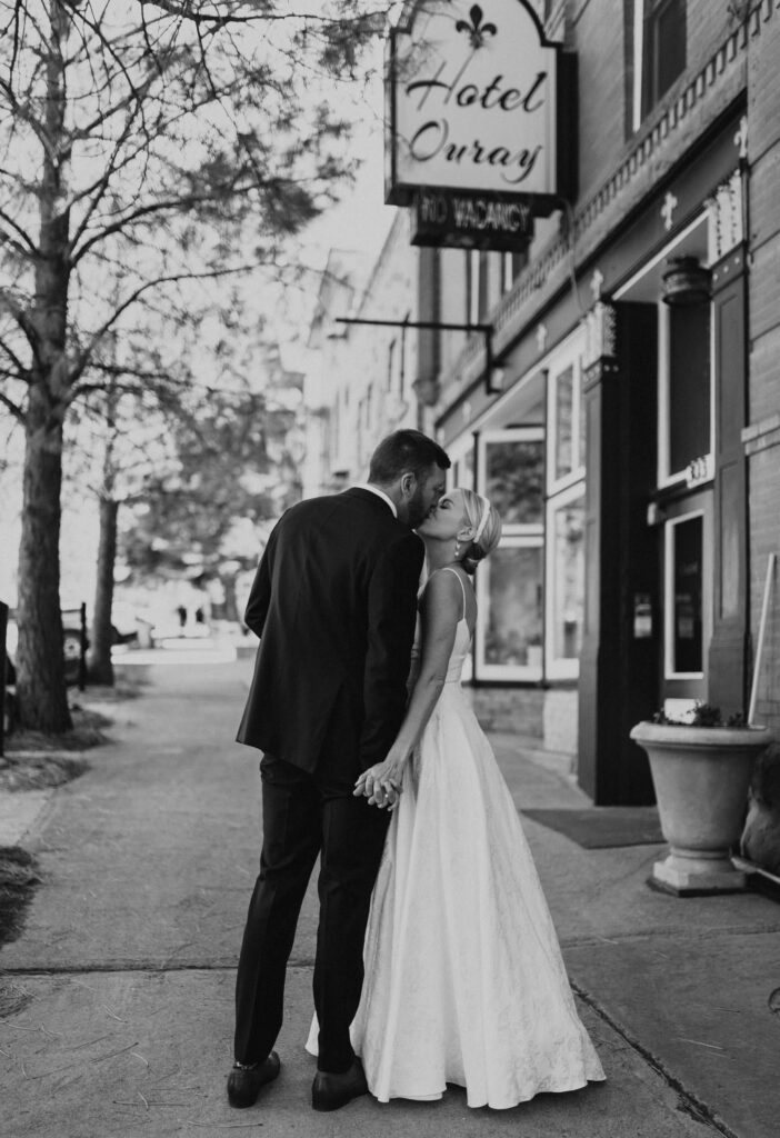 Bride and groom kissing on sidewalk in front of The Beaumont Hotel in Ouray, Colorado