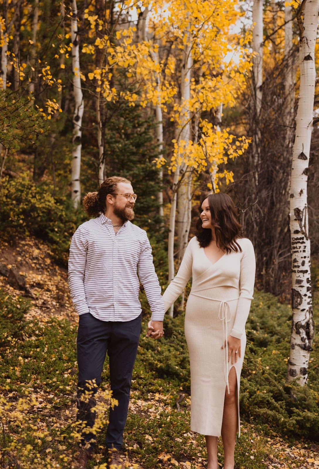 Couple posing for engagement photos surrounded by trees