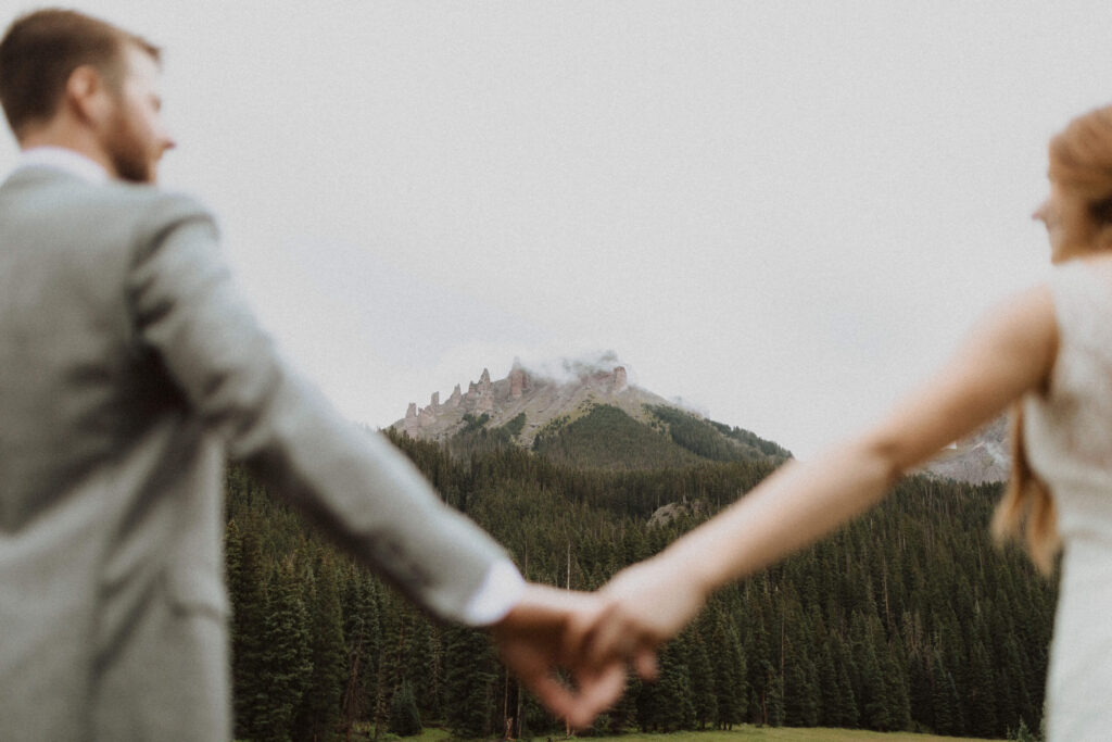 Bride and groom holding hands and facing the San Juan Mountains