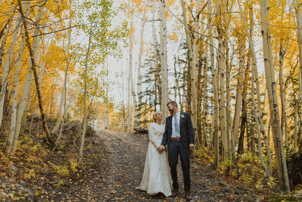 Bride and groom posing for elopement photos surrounded by trees